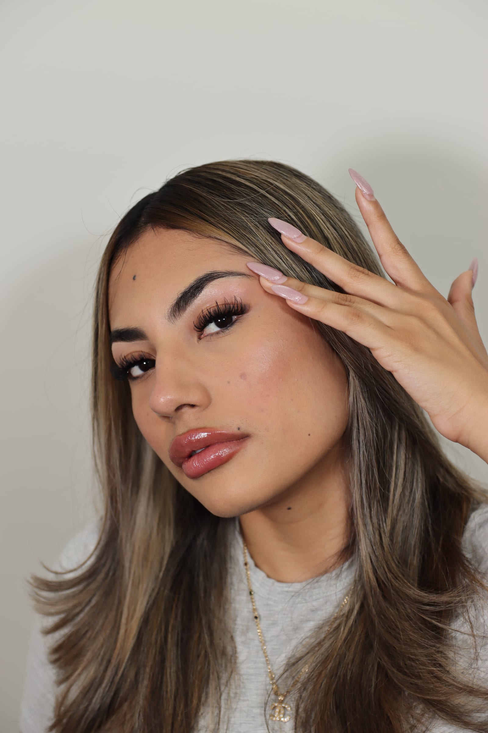 Portrait with one hand at the temple highlighting a finished lash look.