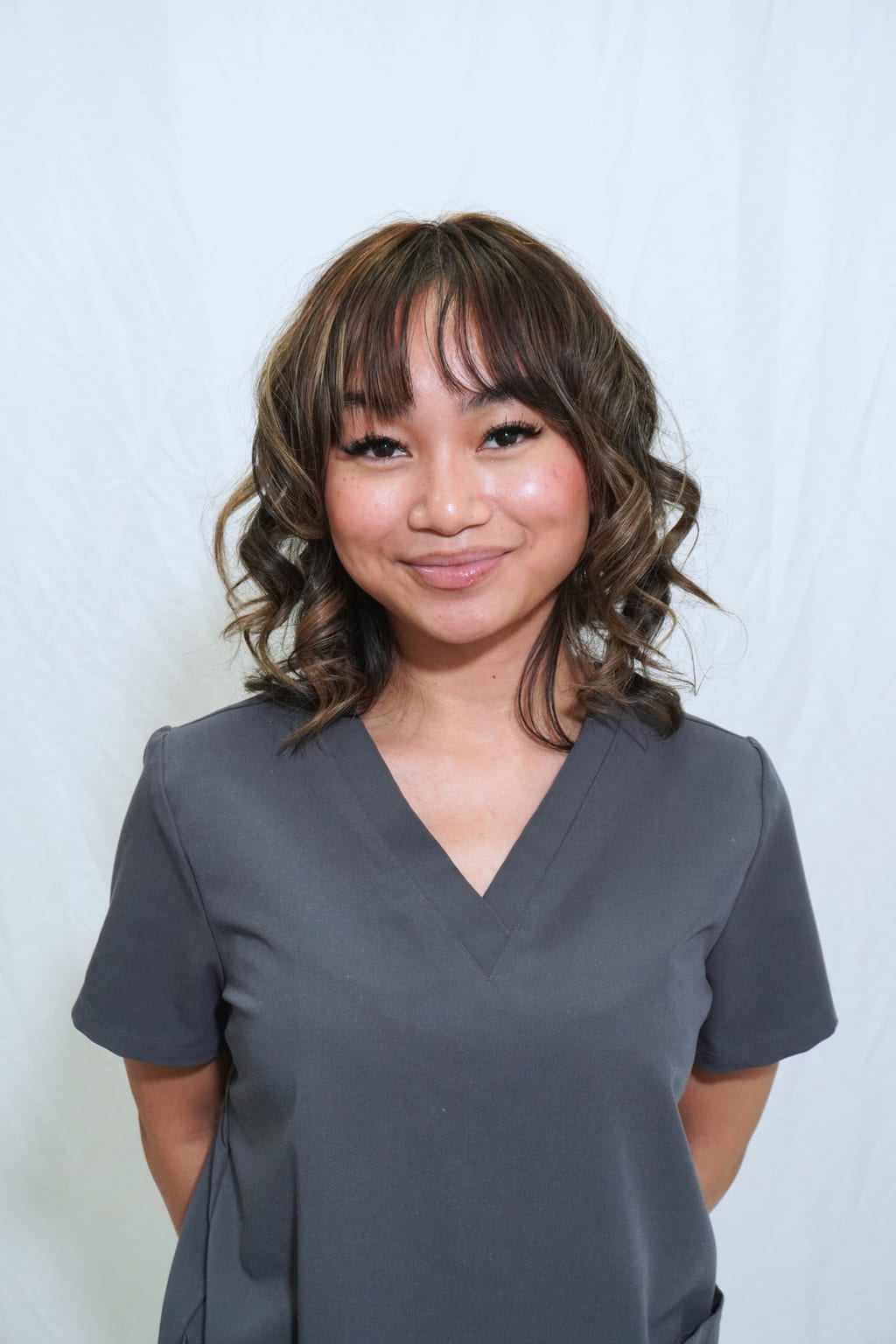 Lauren standing in a gray salon uniform.