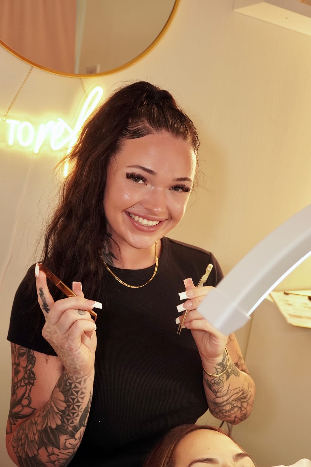 Margaux seated in the salon holding lash tools.