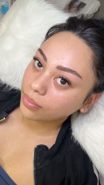 Reclining portrait highlighting defined brows and lashes.